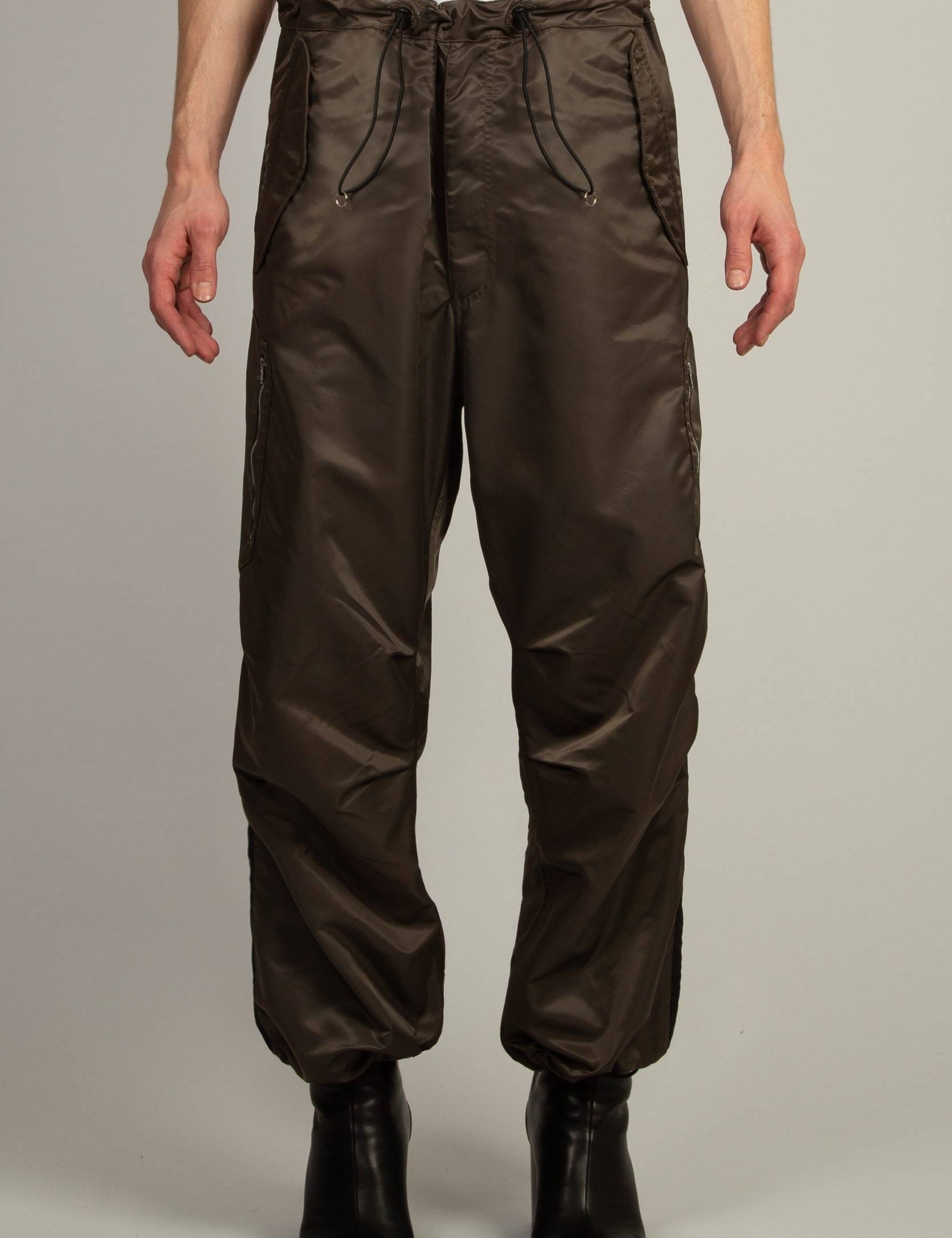 Random Identities Berlin Baggies in Bronze, relaxed nylon pants with drawcord waist and hem, officer stripe and zip patch pocket