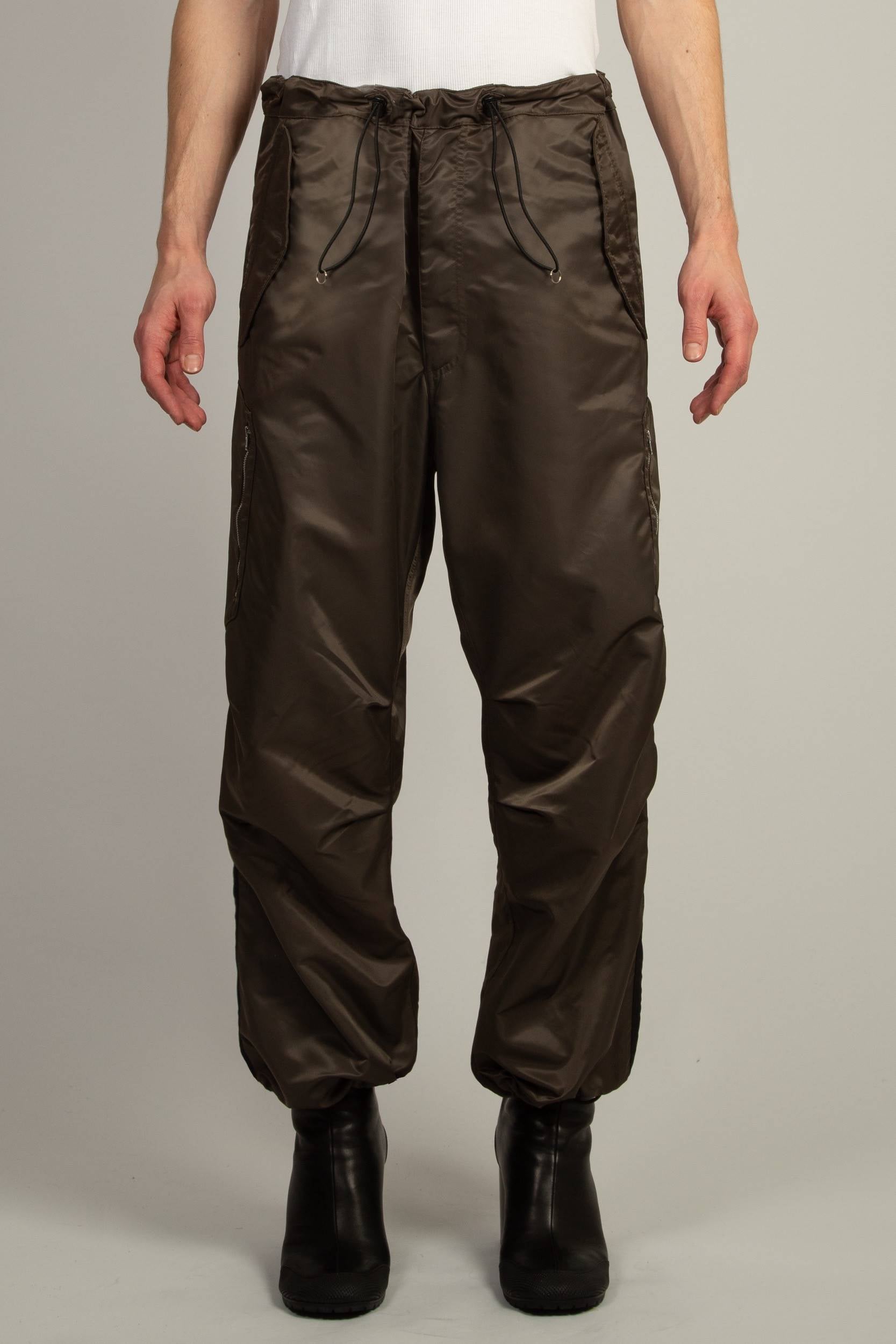 Random Identities Berlin Baggies in Bronze, relaxed nylon pants with drawcord waist and hem, officer stripe and zip patch pocket