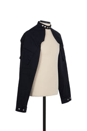 Black cotton shrug jacket by Random Identities. front view with press buttons