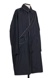Black nylon raincoat with contrast piping, flap pockets, sleeve zip pocket and single vent by Random Identities