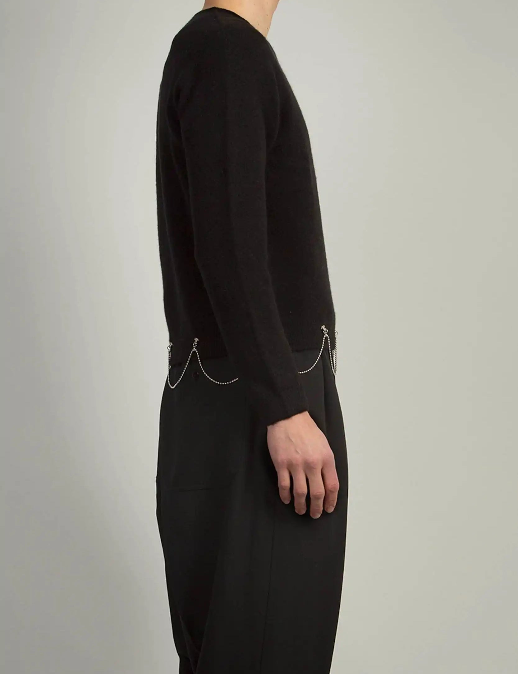 Black crew neck knit by Random Identities featuring 1x1 rib trims and chain detail at hem, styled with tailored trousers
