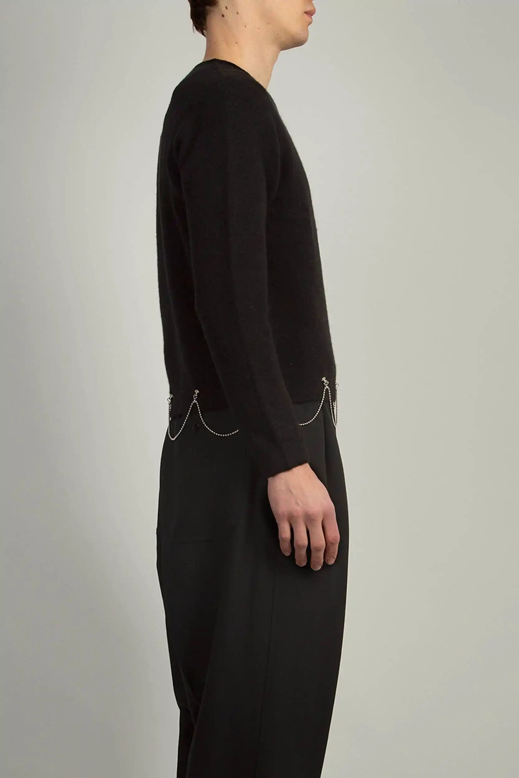 Black crew neck knit by Random Identities featuring 1x1 rib trims and chain detail at hem, styled with tailored trousers