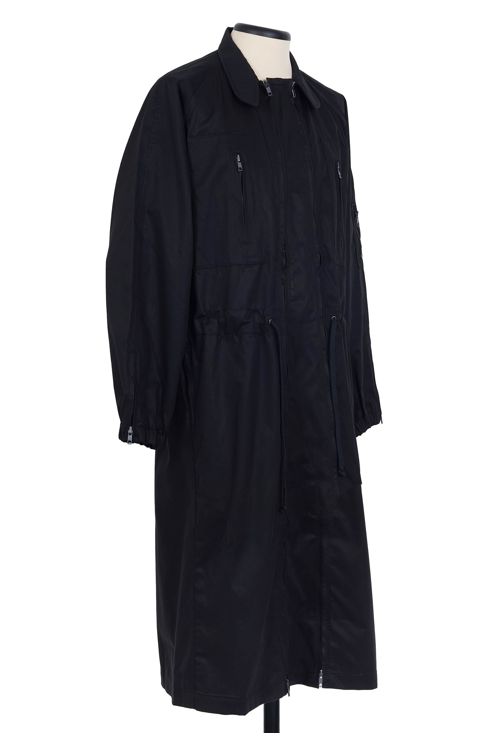 Black cotton gabardine coat. spread collar, zip chest and waist pockets, upper‑sleeve zip pocket