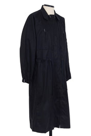 Black cotton gabardine coat. spread collar, zip chest and waist pockets, upper‑sleeve zip pocket