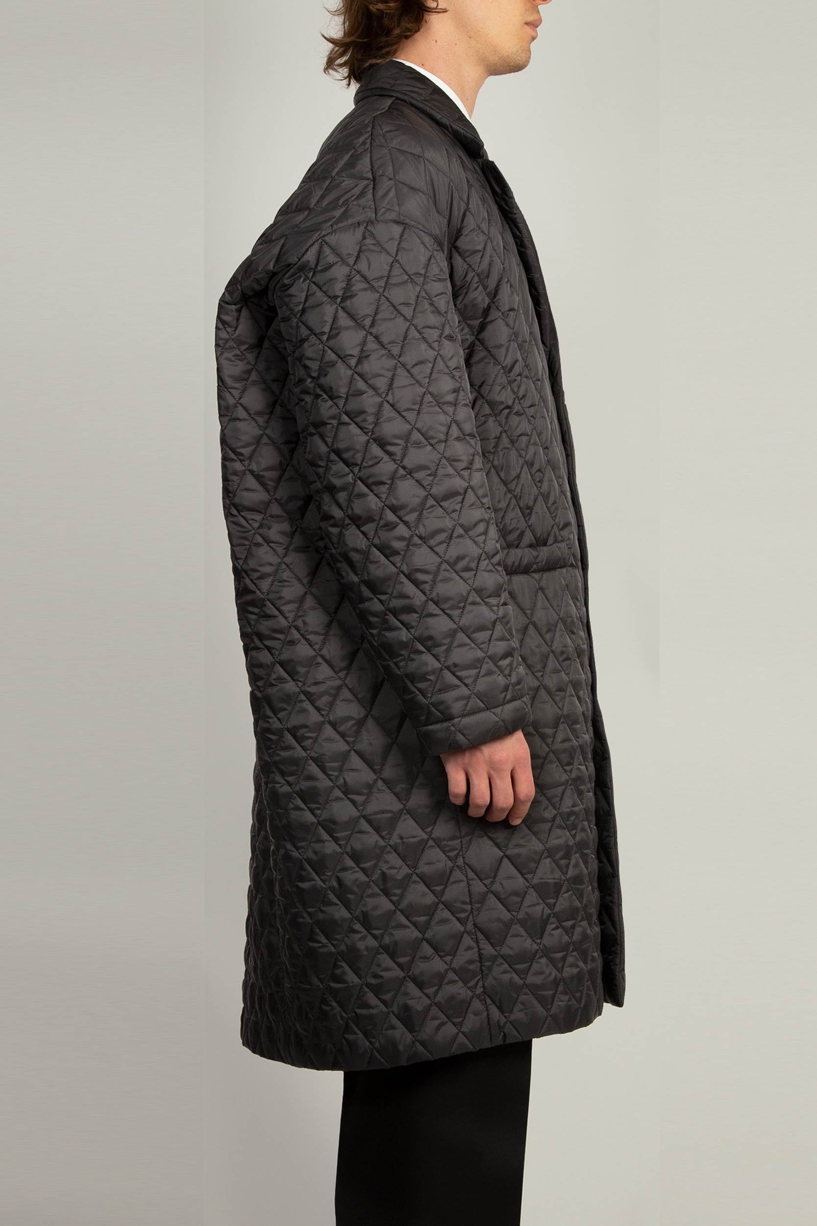 Black single breasted coat with front welt pockets and rounded back profile