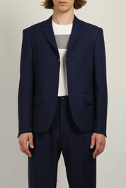Random Identities Buttonless Blazer in Navy, gaberdine blazer with notch lapel, flap pockets, and metal rivet detailing, front view